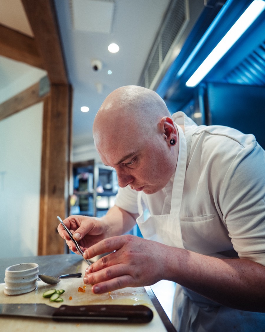 Dan Merriman placing a garnish with tweezers at the kitchen pass